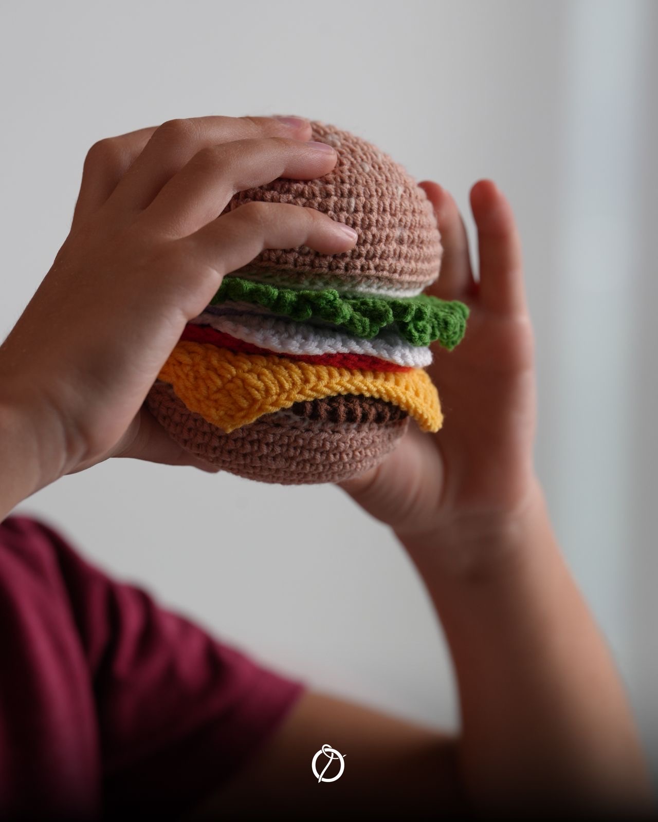 Child holding a layered handmade crochet hamburger
