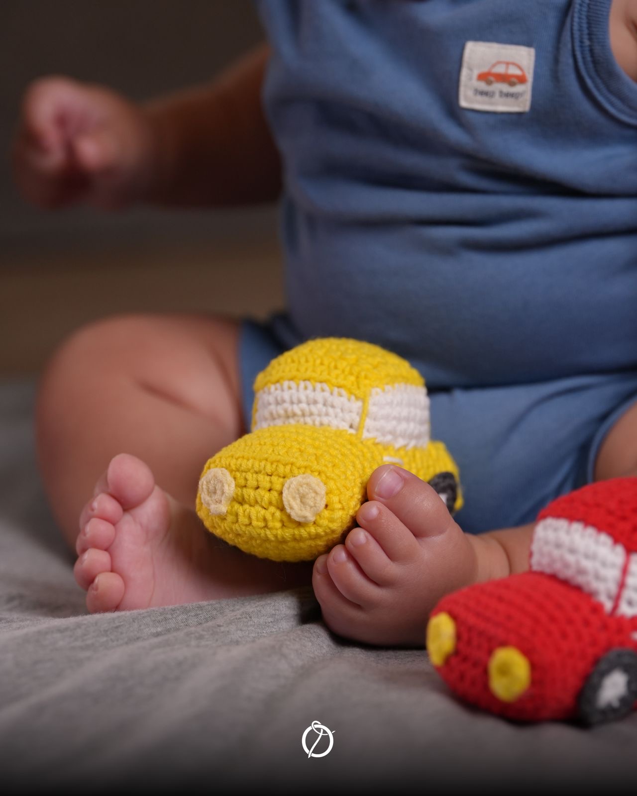 Baby playing with yellow and red crochet cars