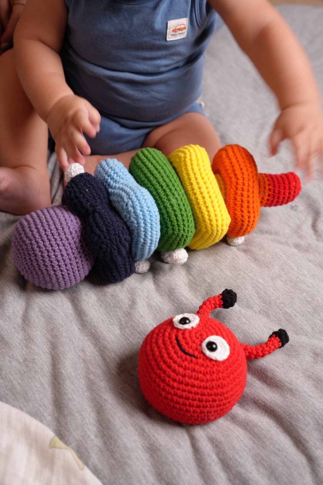Toddler playing with rainbow crochet caterpillar stacker