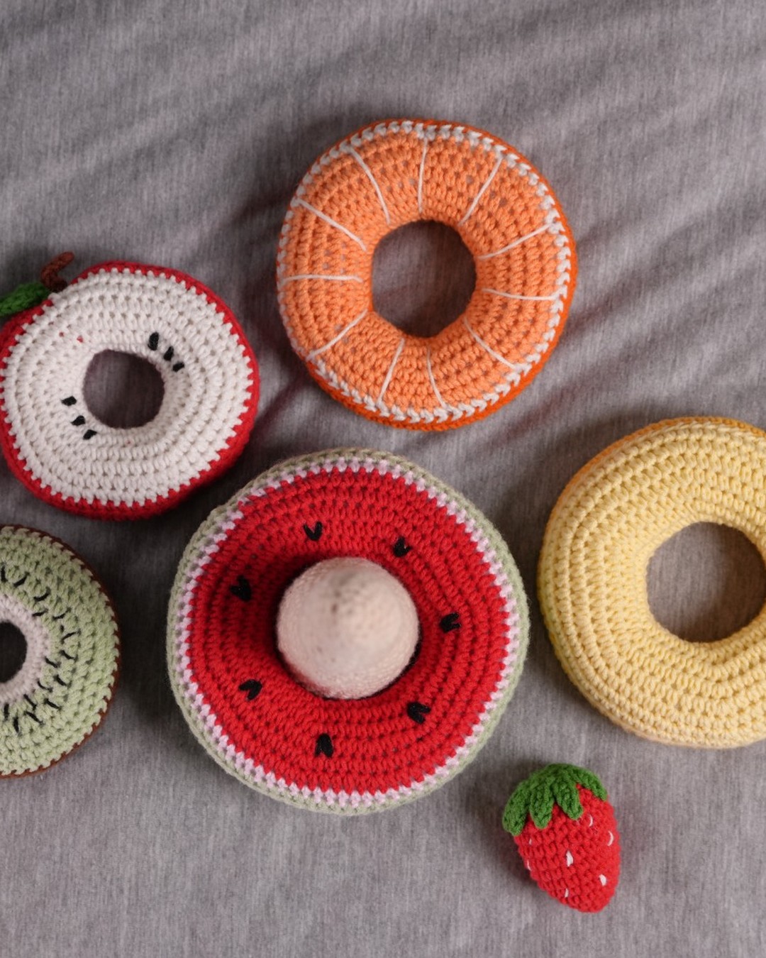 Baby playing with crochet fruit stacking rings and strawberry topper