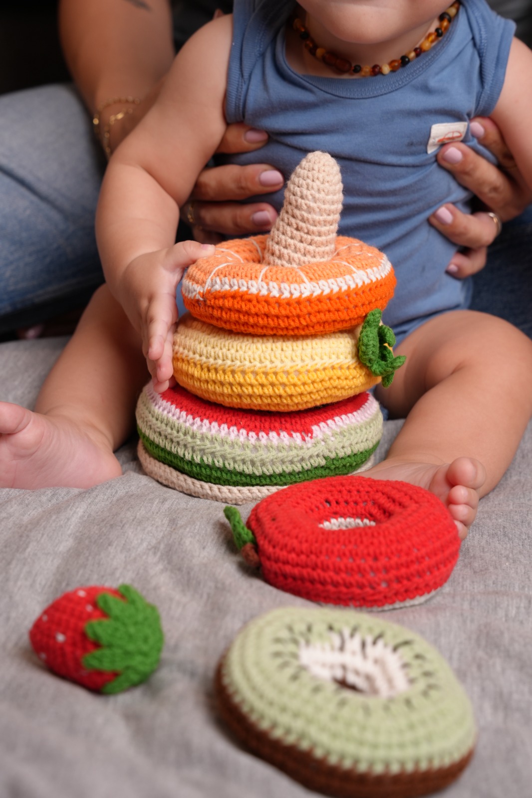 Baby playing with crochet fruit stacking rings and strawberry topper