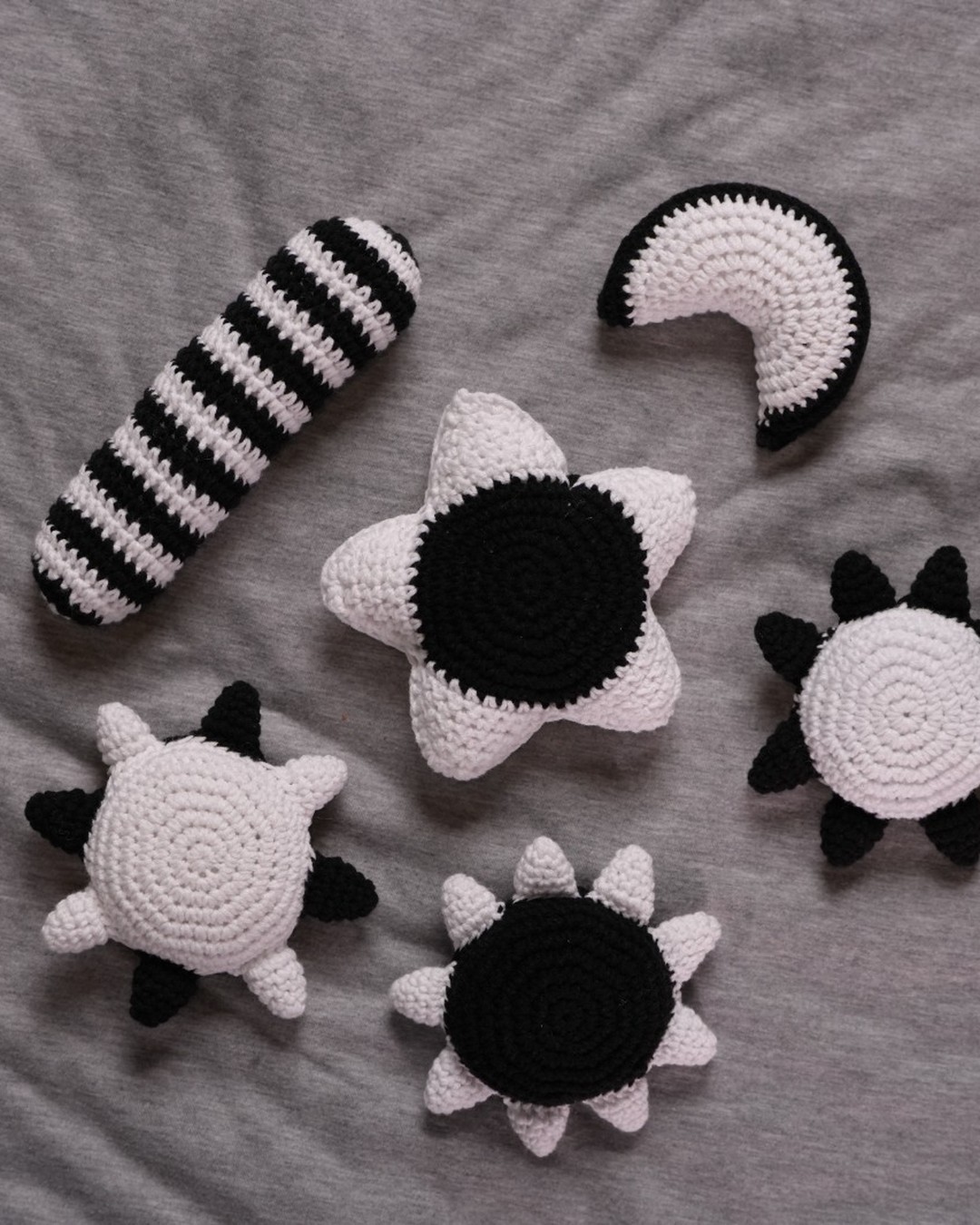 Black and white high-contrast crochet sensory toys including suns, moon and striped cylinder