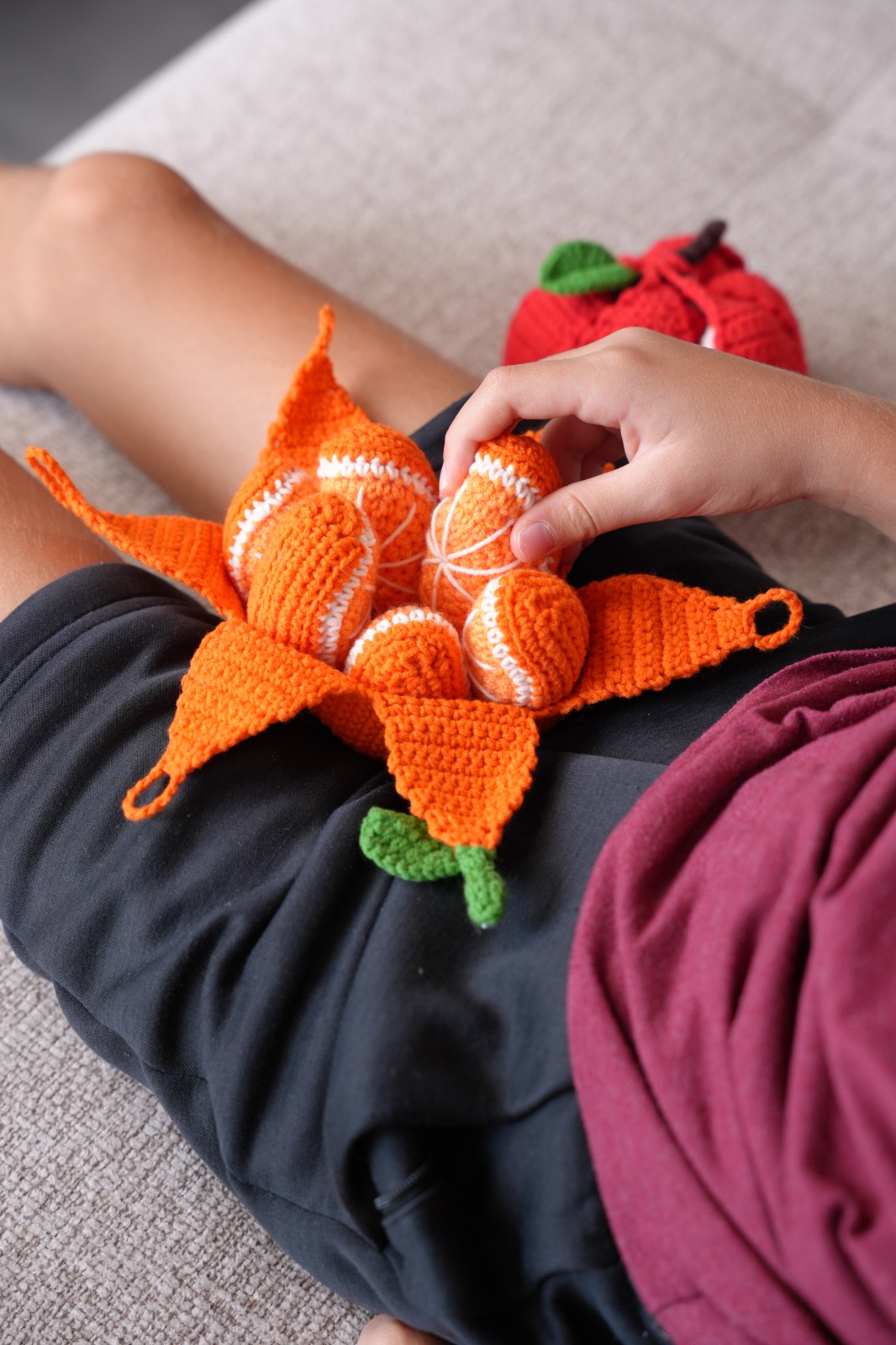 Child peeling open the crochet orange to reveal segments