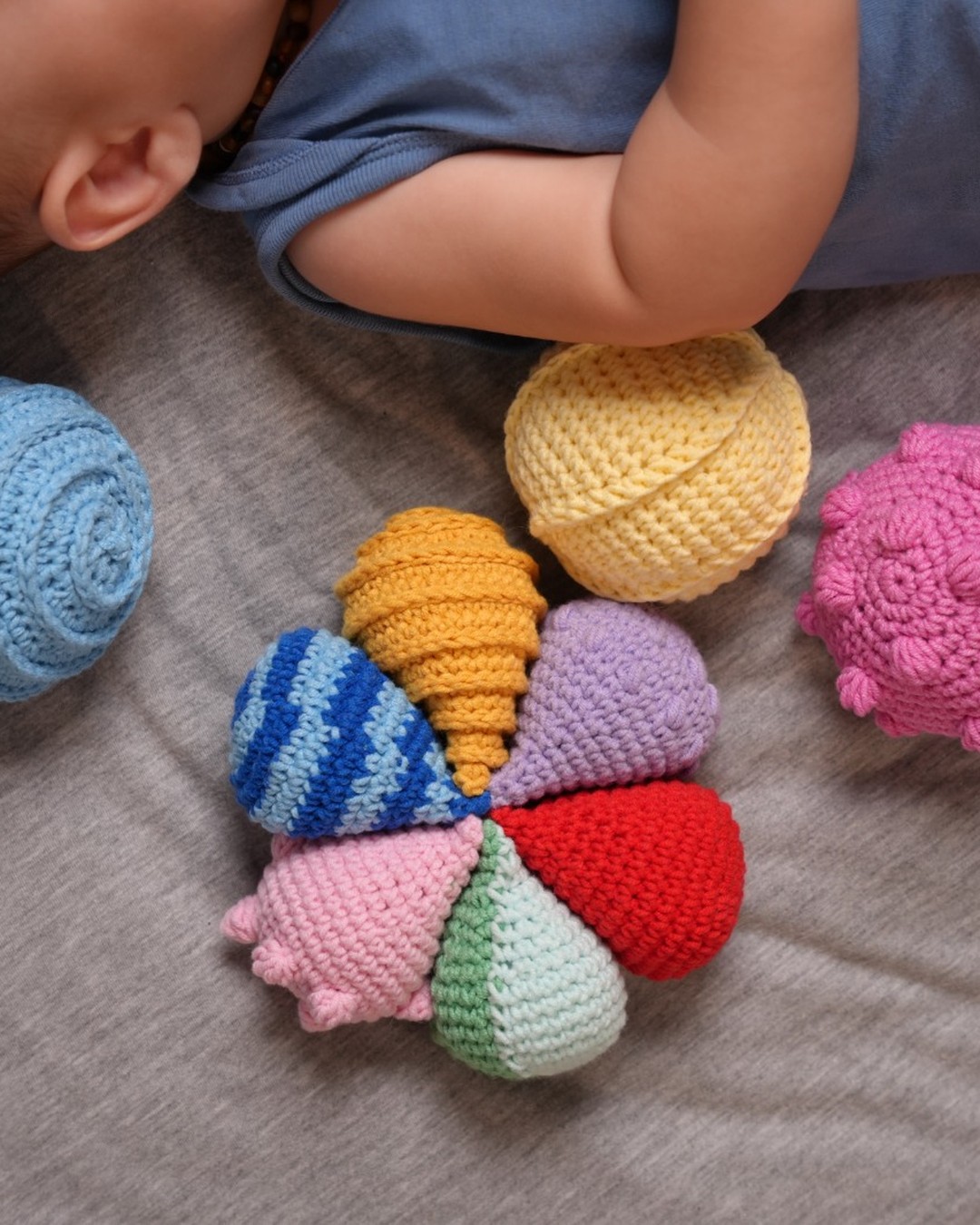 Baby exploring crochet sensory balls on a soft blanket