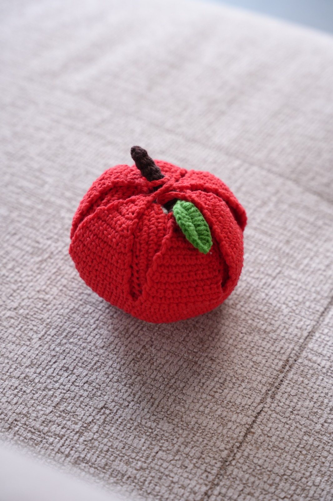 Close-up of handmade crochet red apple with green leaf