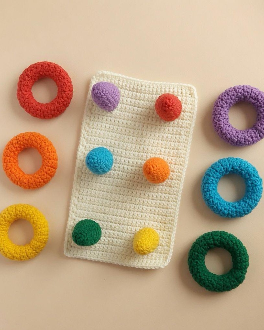 Cream crochet board with six coloured pegs and matching rings