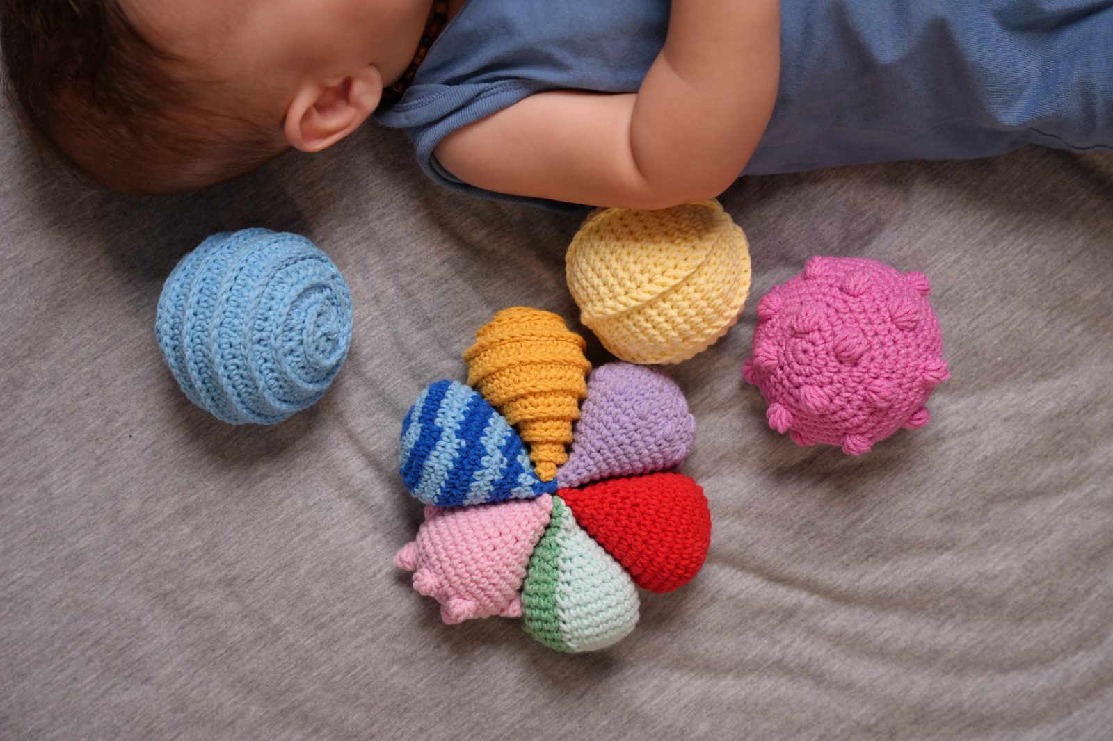 Baby exploring crochet sensory balls on a soft blanket
