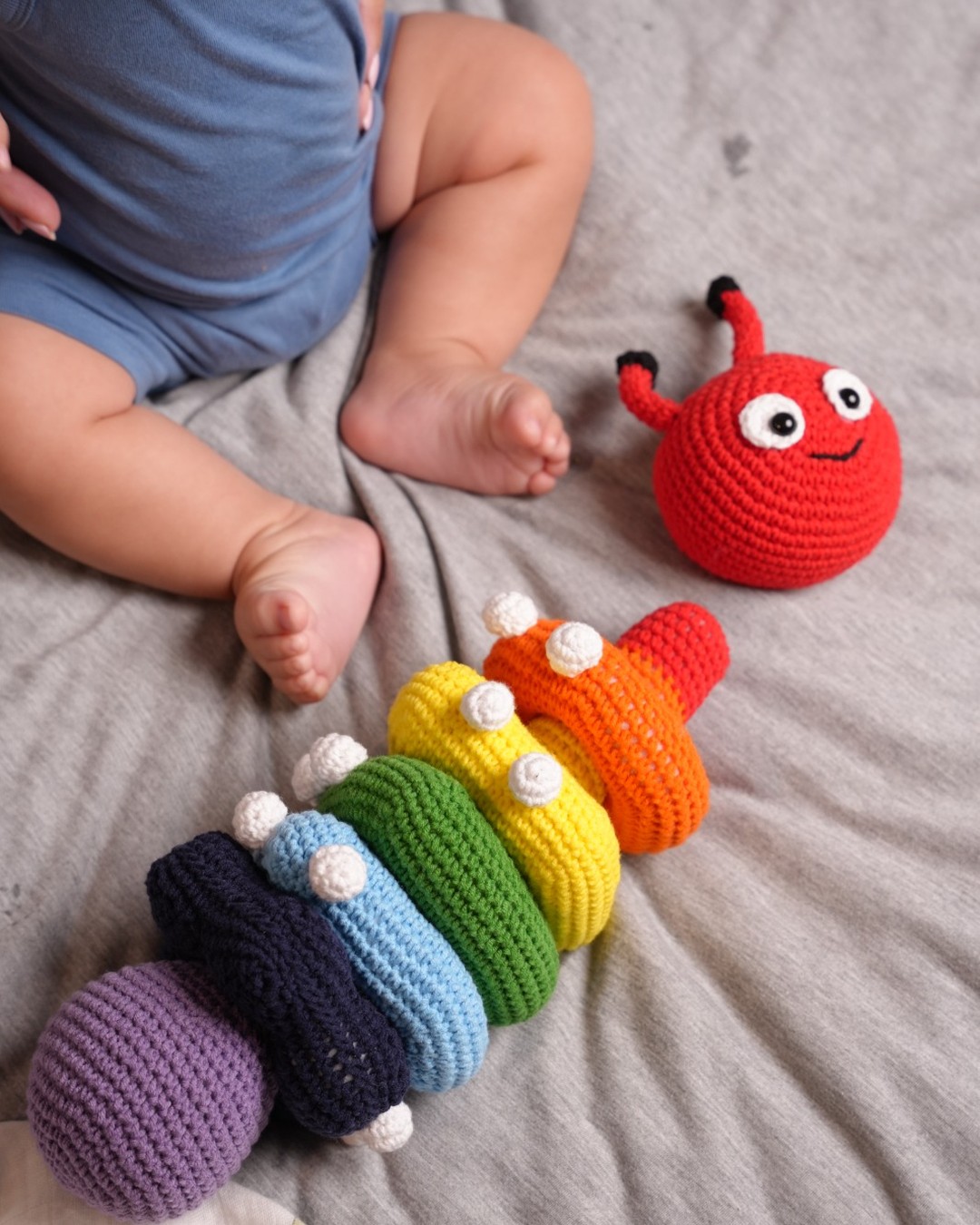 Toddler playing with rainbow crochet caterpillar stacker