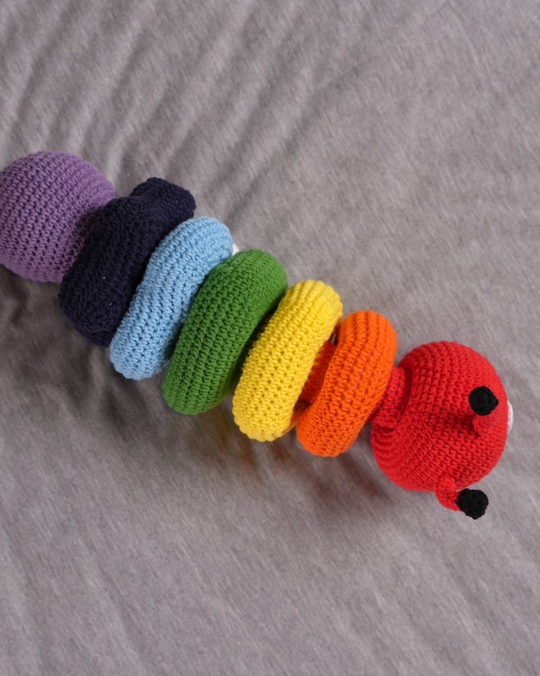Rainbow crochet caterpillar with a red head and colourful body segments